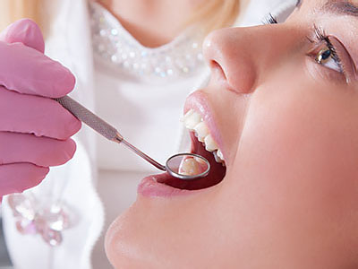 An individual receiving dental care with a dentist using specialized tools.